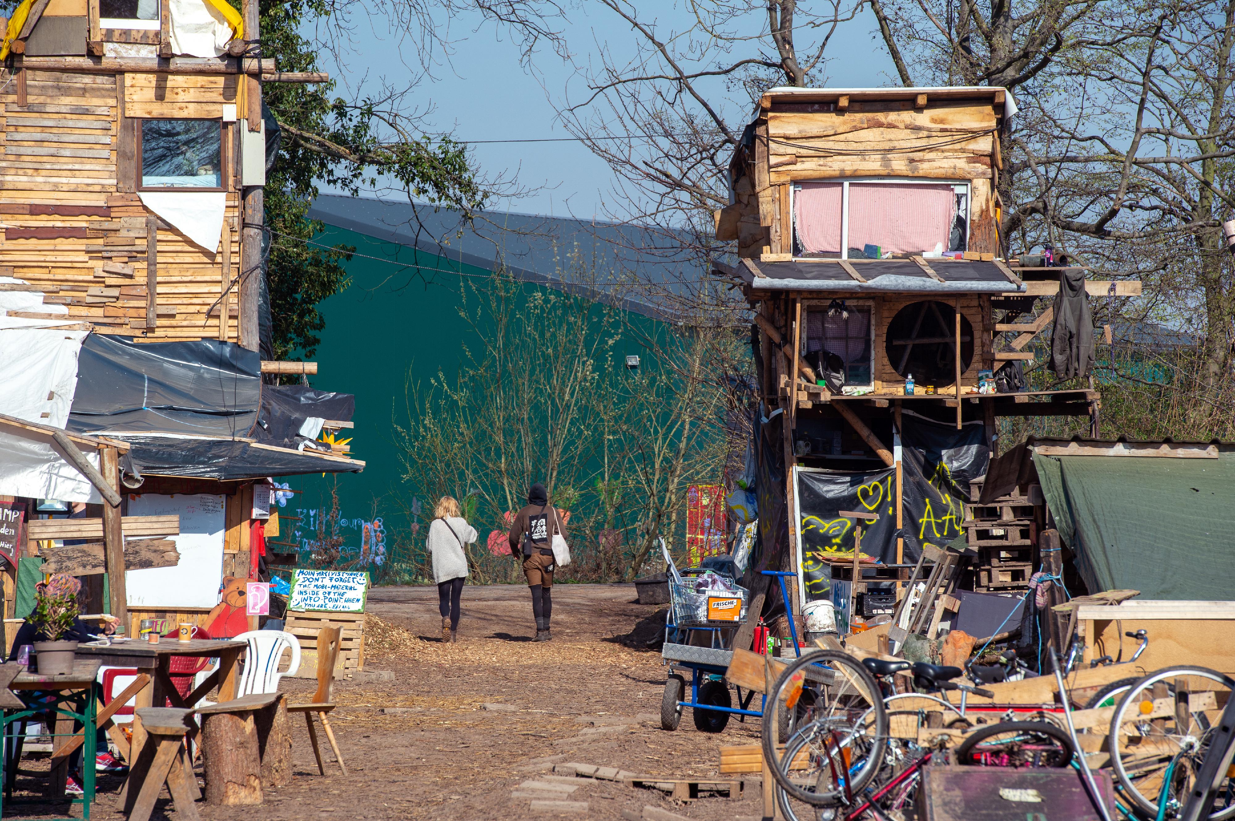 Dorfausgang von Lützerath mit Sicht auf Halle, links und rechts jeweils ein selbstgebauter, bewohnter Turm.