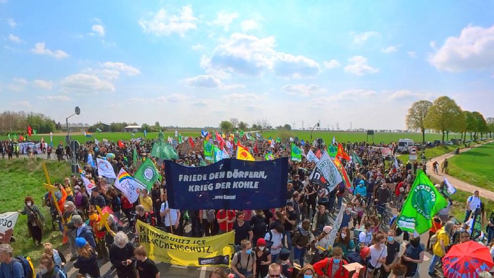 Foto der FFF Demo vom 23. April mit verschiedenen Bannern Friede den Dörfern - Krieg der Kohle. Fridays for Future, Klimaschutz ist Menschenschutz, Atomkraft? Nein Danke, Pax Christi