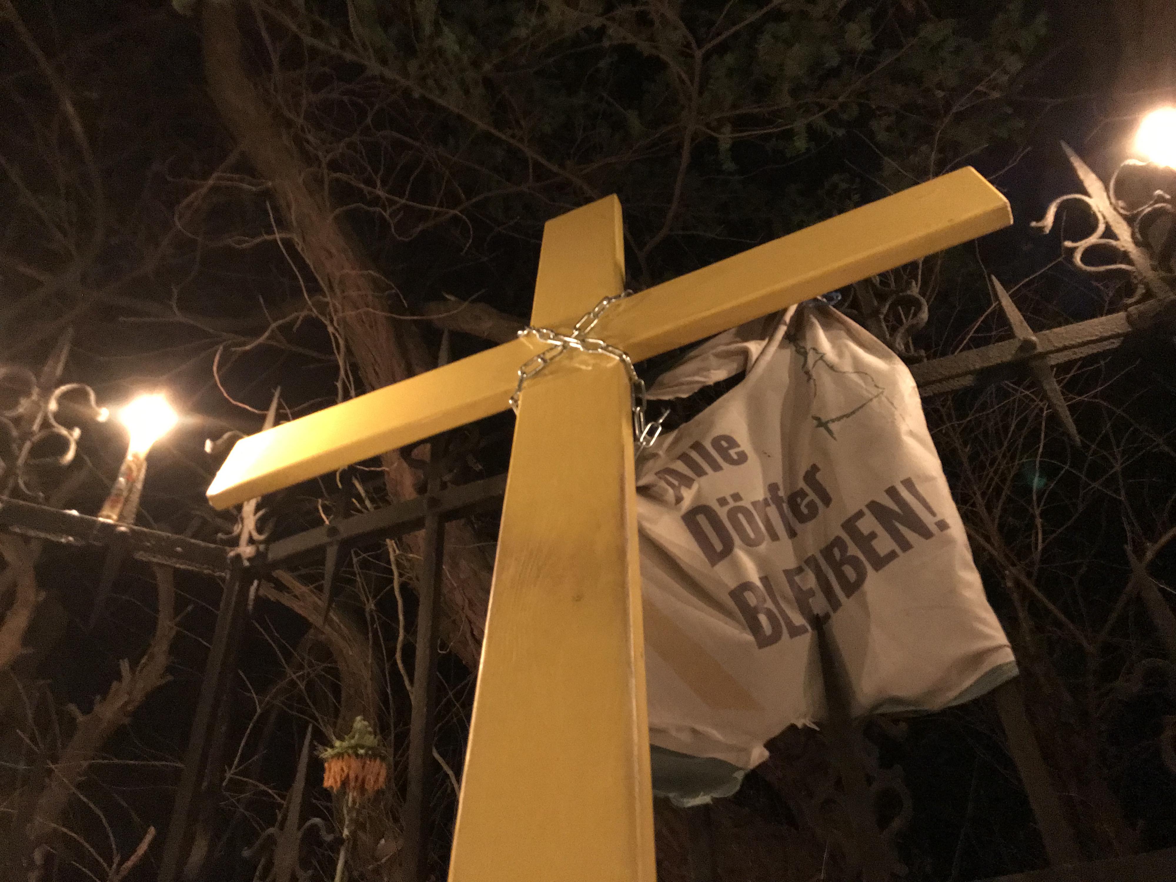 Nächtliche Eibenkapelle mit dem von Gorleben nach Lützerath getragenen Kreuz und einer Fahne mit der Aufschrift Alle Dörfer bleiben.