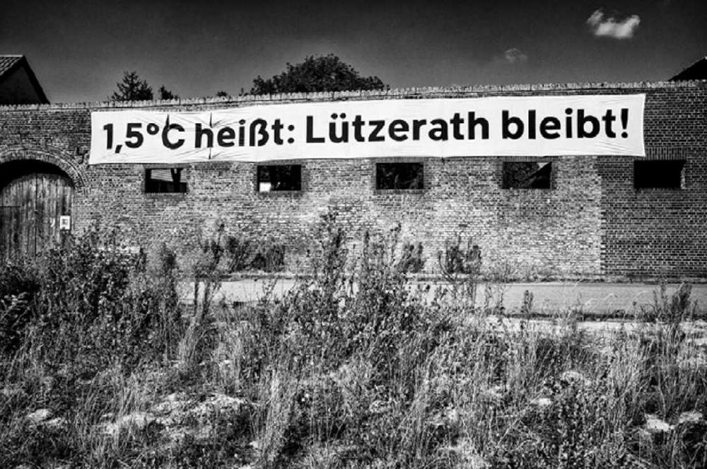 Schwarz-weißes Bild von Eckardts Hof mit dem Banner 1,5°C heißt: Lützerath bleibt!