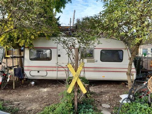 Wohnwagen im Bewegungsgarten mit gelbem X vor der Tür.